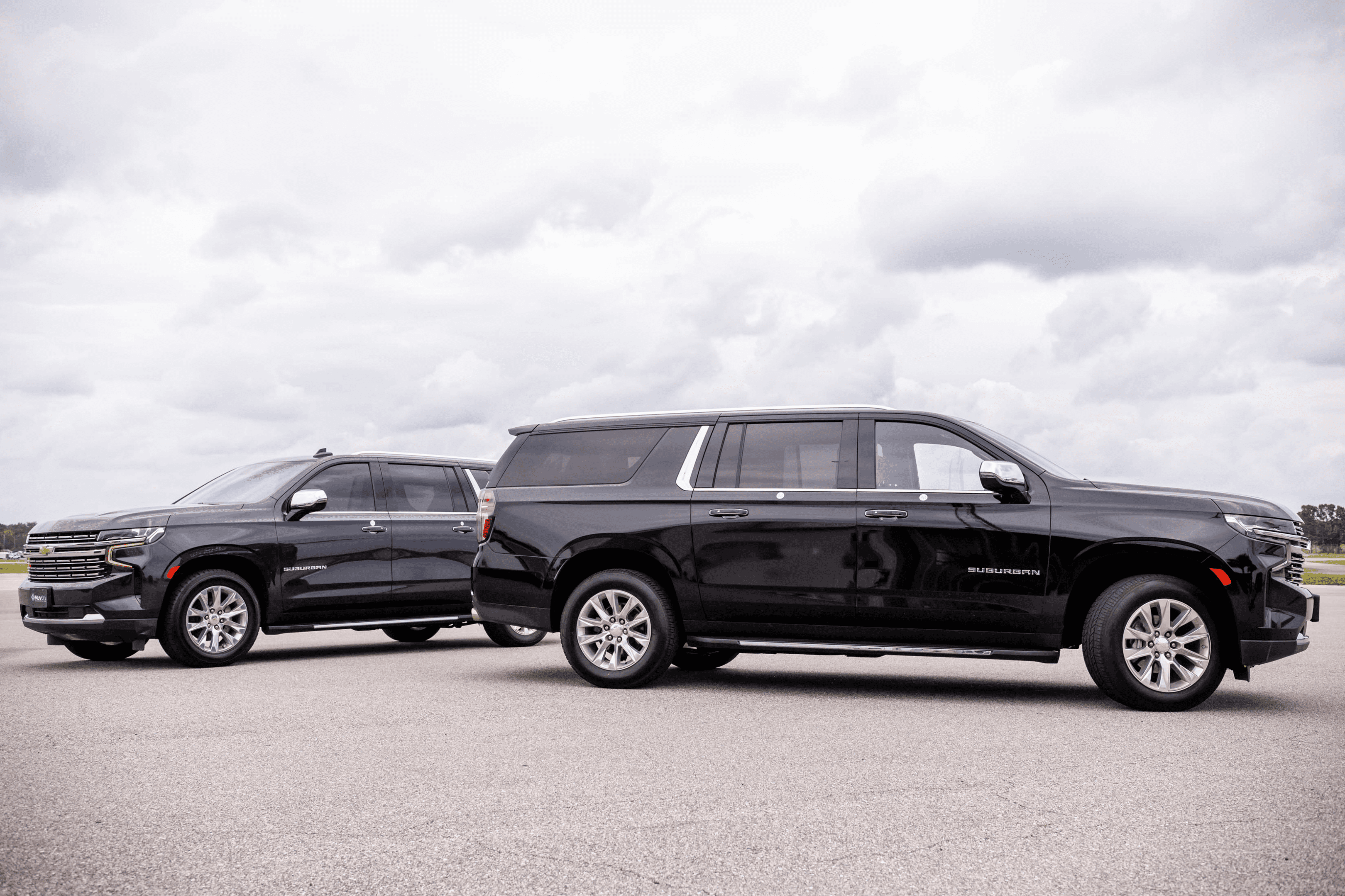 Two black SUVs parked under cloudy sky