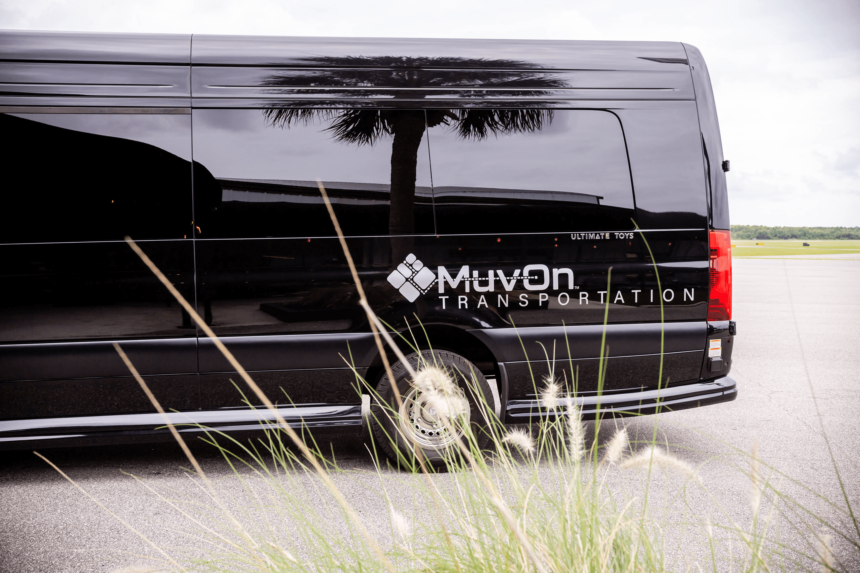 Black MuvOn shuttle van with palm reflection