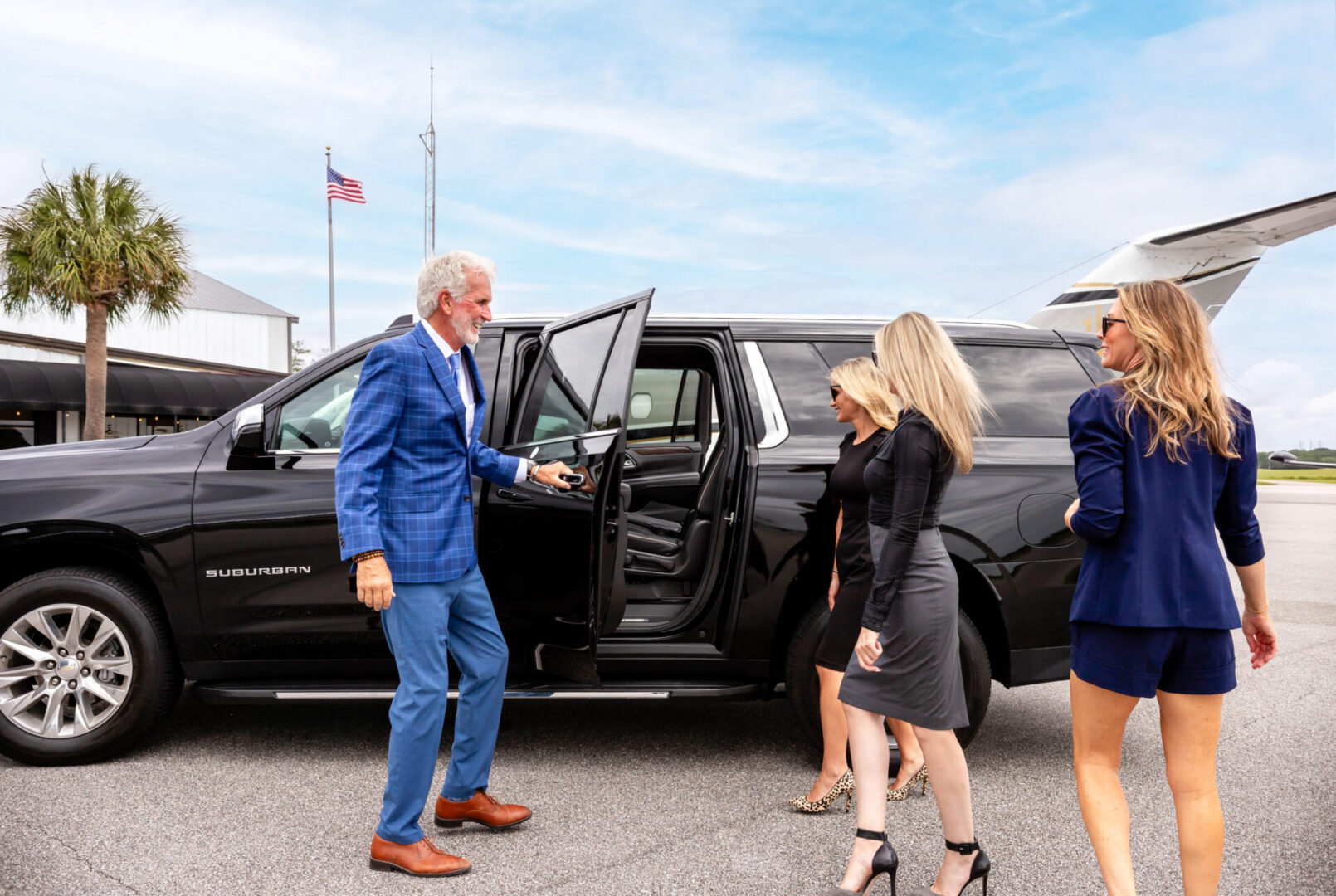 Man opening SUV door for three businesswomen